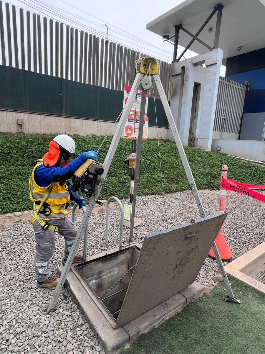 Trabajador con trípode y equipo de rescate en un espacio confinado